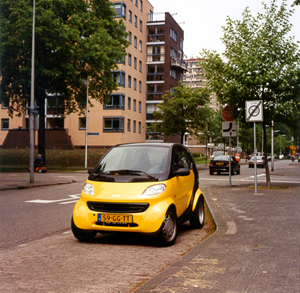 A yellow Smart car