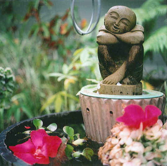 A statue of a smiling figure atop a wine barrel pond